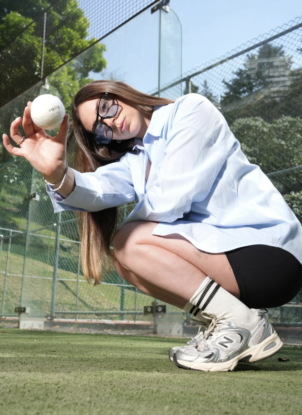 Rally: woman crouching on a padel court holding a Rally ball